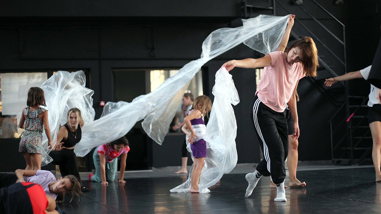 dancers connected with each other via a very long piece of plastic foil