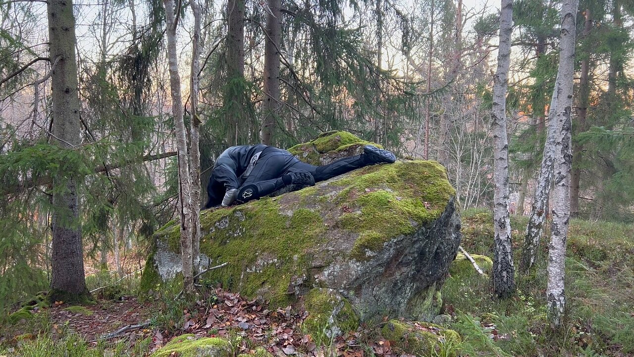 Person lying on a stone in the woods