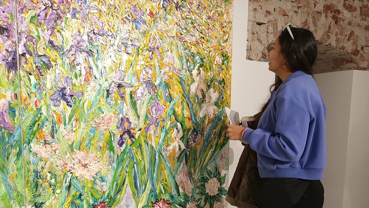 Andrea Vezga looking at an enormous painting of flowers